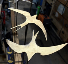 Load image into Gallery viewer, Metallic sculpture of a Swallow in flight on a blurred workshop background